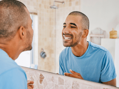 Man looking at his smile in mirror | Nudera Orthodontics