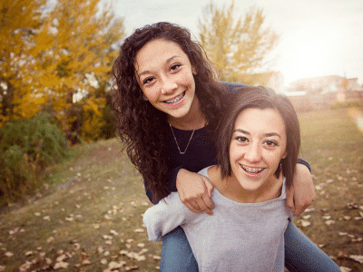 Two young women hugging and smiling | Nudera Orthodontics