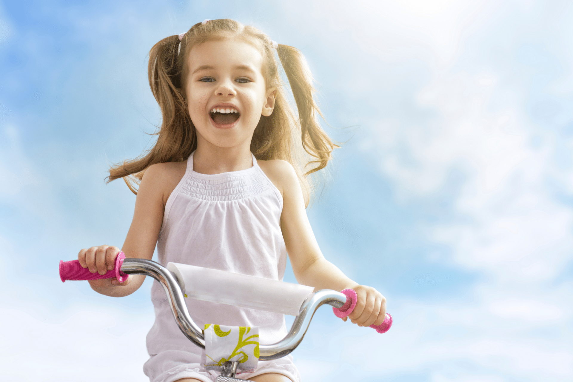 Smiling young girl riding a bicycle outdoors